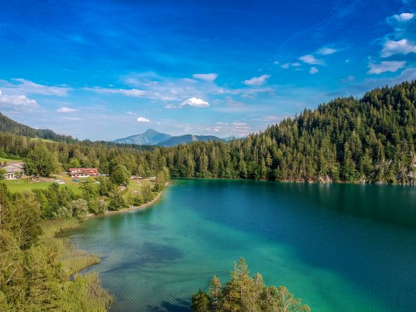 Blue waters of Hintersteiner lake surrounded by green pinetrees. The end point of stage 2 on the self-guided Adlerweg trip with Alpine Exploratory