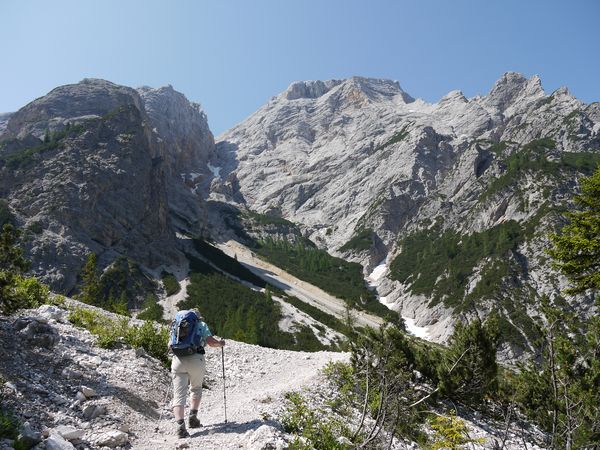 A walker climbing towards the mountains of Croda de Becco on the Alta Via 1 from Lago di Braies to Rifugio Sennes